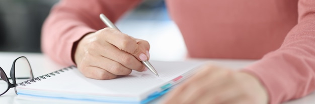Mulher segura a caneta nas mãos e faz anotações no diário. planejando e definindo o conceito de tarefas diárias