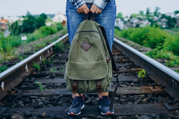 Mulher segura a mochila e fica na ferrovia.