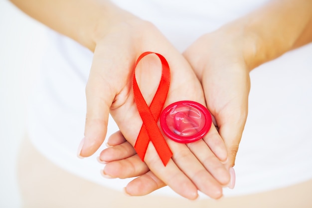 Mulher segura camisinha e fita vermelha, alerta contra a aids