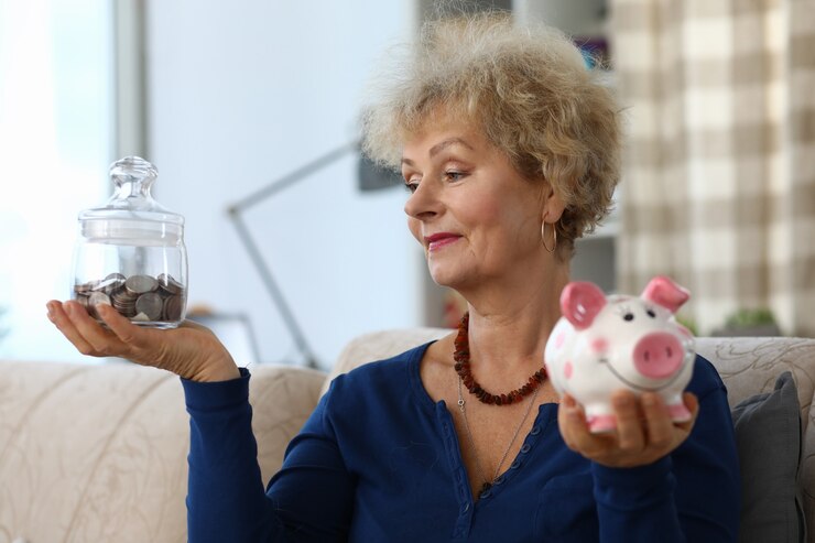 Foto mulher segura cofrinho com economias nas mãos dela.