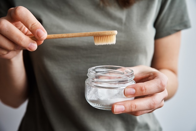 Mulher segura escova de dentes de bambu e pó dental. Conceito de desperdício zero e produtos ecológicos