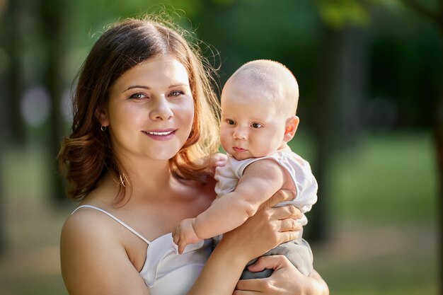 Mulher segura o bebê nas mãos no jardim da cidade