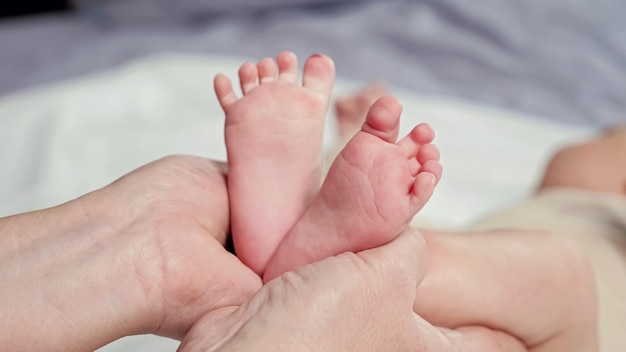 Mulher segura os pés descalços do bebê recém-nascido fazendo forma de coração