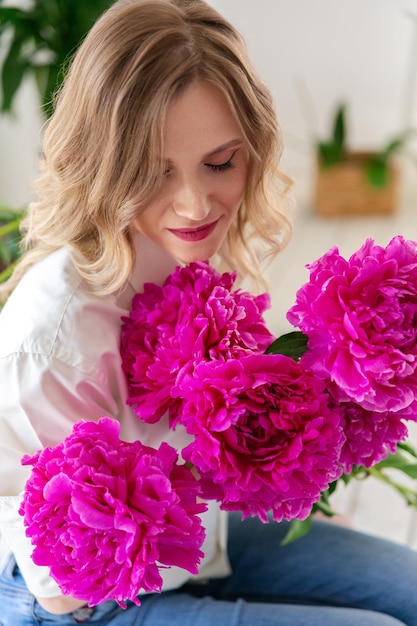 Mulher segura peônias em suas mãos Surpresa de flores para o dia das mães ou dia dos namorados