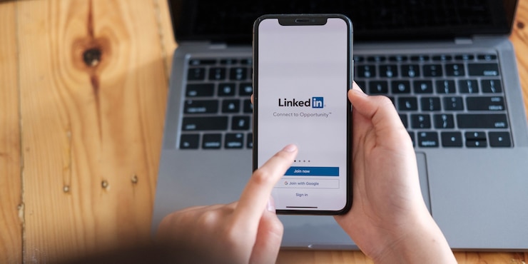 Foto mulher segura smartphone com aplicativo do linkedin na tela