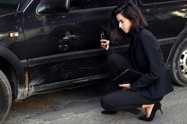 Mulher segura smartphone móvel fotografando acidente de carro para seguro