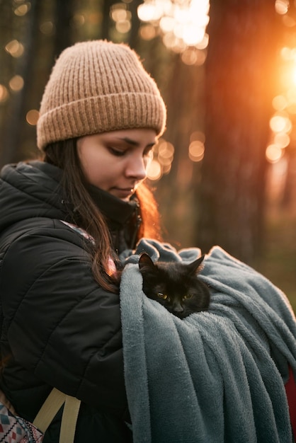 Mulher segura um gato no parque Conceito de se divertir com um gato doméstico preto no parque e ao ar livre