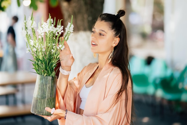 Mulher segura um vaso de flores no café de rua