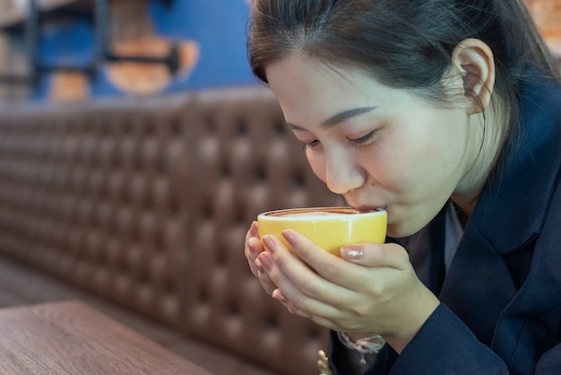 Mulher segura xícara de café e bebida na cafeteria