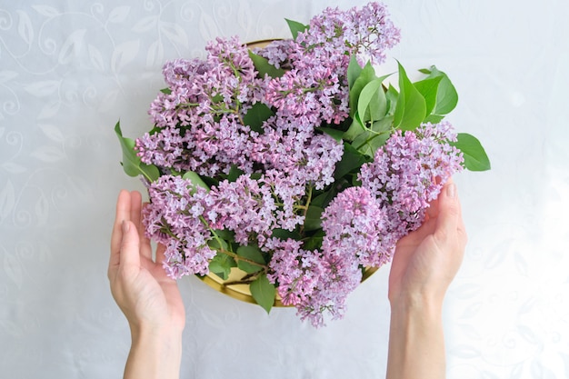 Mulher segurando a bandeja dourada com flores nas mãos para decoração de interiores