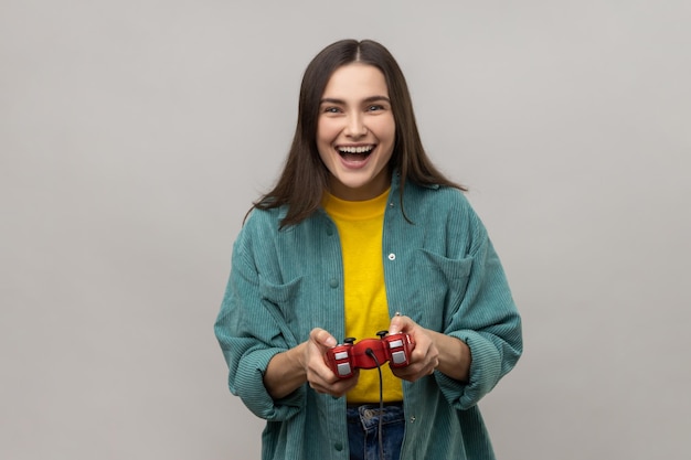 Mulher segurando a competição de videogame vencedora do gamepad olhando para a câmera com expressão feliz