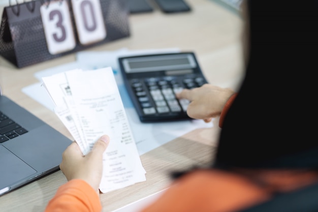 Mulher segurando a conta e usando a calculadora e calcular a conta de custo e pagamento.