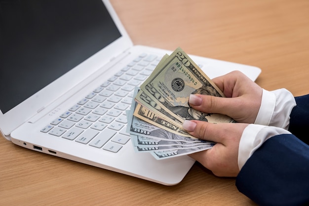 Mulher segurando a moeda de um dólar no laptop branco