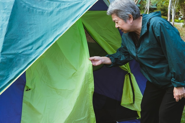 Foto mulher segurando a porta da tenda enquanto está de pé em terra