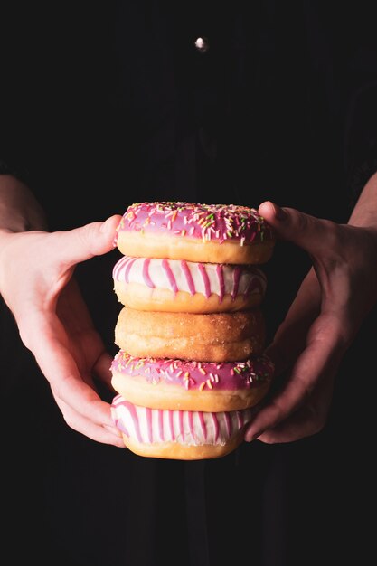 Mulher segurando alguns donuts multicoloridos