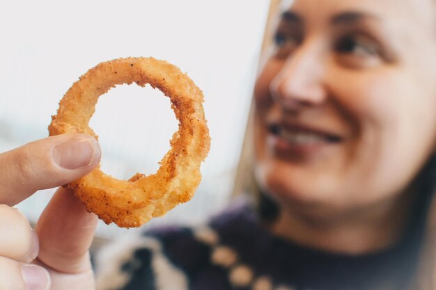 Foto mulher segurando anel de cebola enquanto está sentada em um café