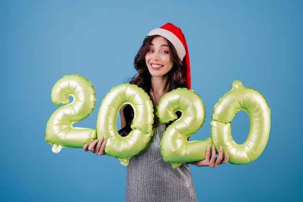 Mulher segurando balões de ano novo com vestido e chapéu de Papai Noel