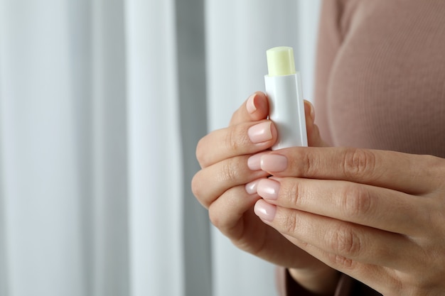 Mulher segurando batom higiênico, espaço para texto