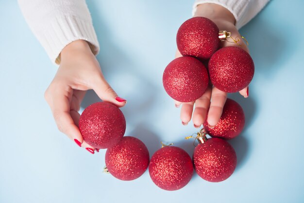 Mulher segurando bolas vermelhas de Natal em uma mãos no azul