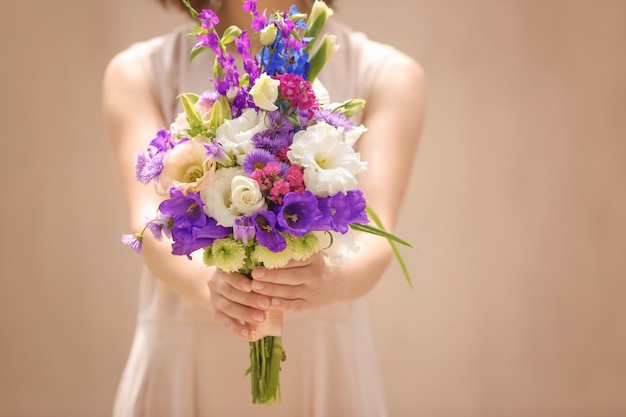 Mulher segurando buquê de lindas flores em fundo bege