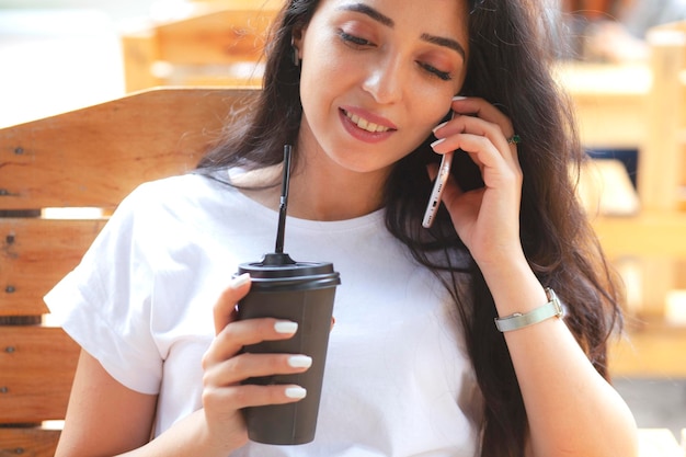 Mulher segurando café e telefone no café