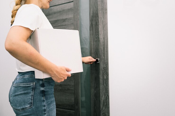 Foto mulher segurando caixas de pacotes de papelão contra a porta da entrada da casa mãos femininas segurando cães de pacotes ecológicos brancos funcionários de armazenamento serviço de entrega