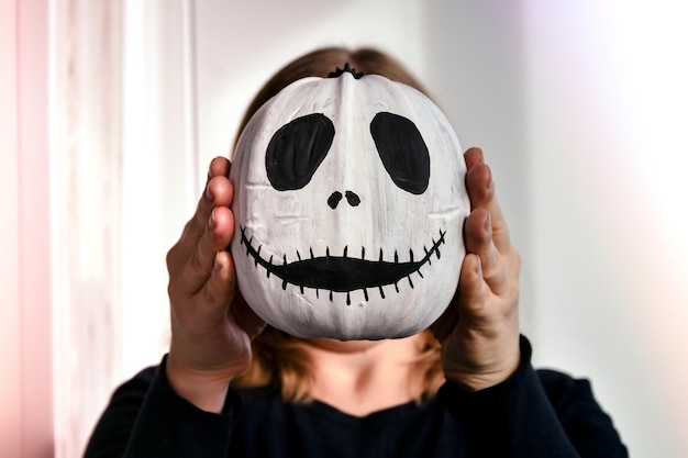 Mulher segurando cara de abóbora engraçada na frente de seu rosto halloween fundo diy fazê-lo você mesmo