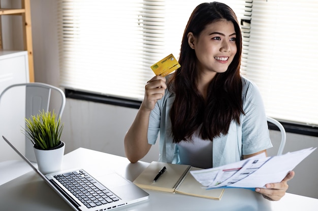 Mulher segurando cartão de crédito e conta com sorriso