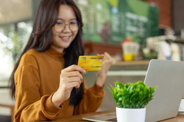 Mulher segurando cartão de crédito e usando computador portátil compras on-line internet banking