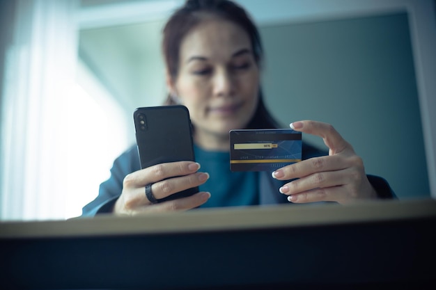 Mulher segurando cartão de crédito e usando smartphone no escritório Compras online de comércio eletrônico internet banking