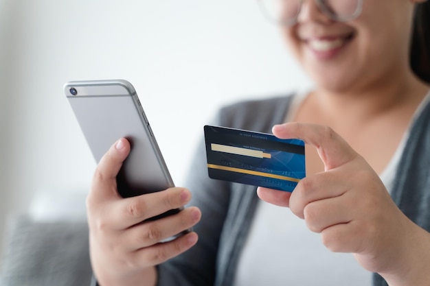 Mulher segurando cartão de crédito e usando smartphone para compras online internet banking gastar dinheiro