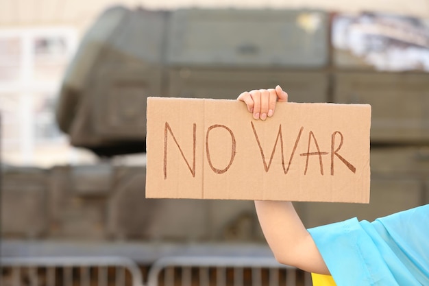 Mulher segurando cartaz com palavras sem guerra ao ar livre closeup