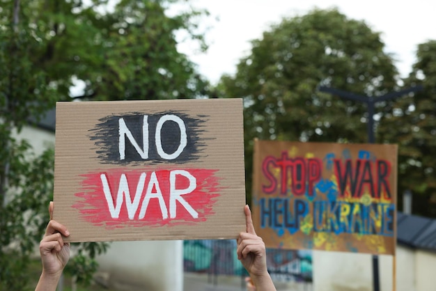 Foto mulher segurando cartaz com palavras sem guerra ao ar livre closeup