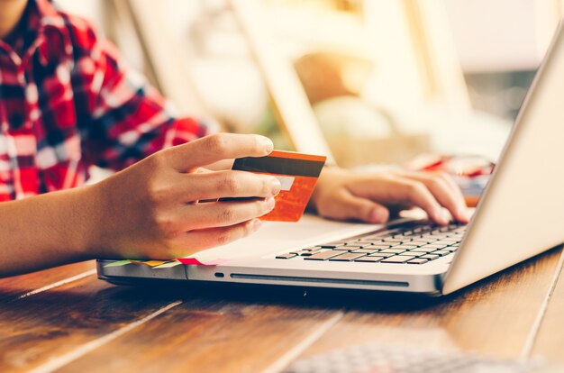 Mulher segurando cartões de crédito e telefones celulares estão agora comprando pela internet pagando