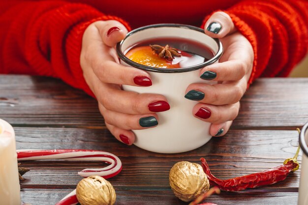 Mulher segurando copo com vinho quente nas mãos