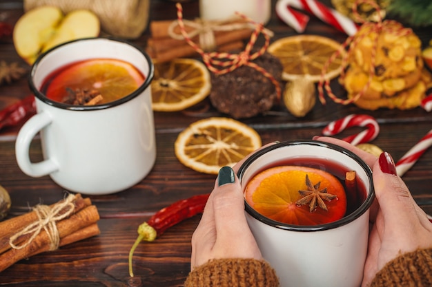 Mulher segurando copo com vinho quente nas mãos