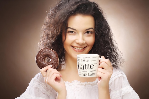 Mulher segurando donut e café