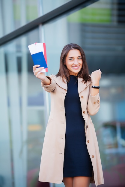 Mulher segurando duas passagens aéreas no exterior passaporte perto do aeroporto