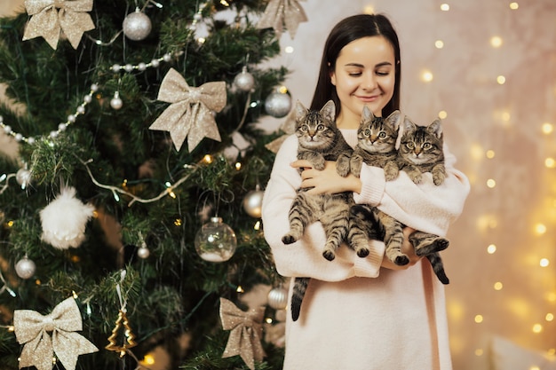 Mulher segurando e olhando para seus três gatinhos