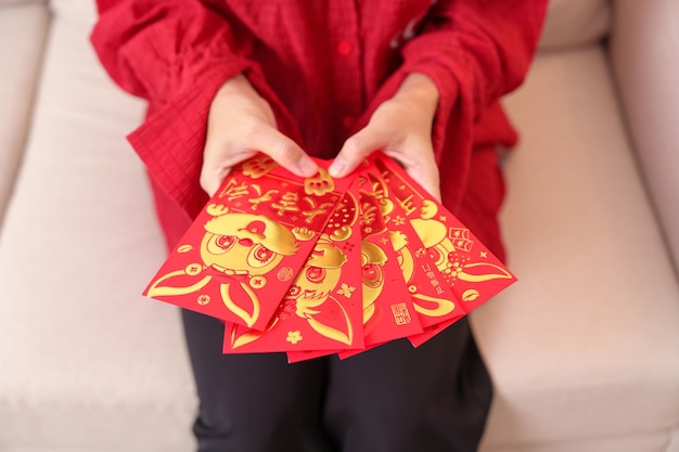 Mulher segurando envelope vermelho chinês com coelho dourado e palavra de bênção presente em dinheiro para feliz feriado do Ano Novo Lunar A frase chinesa significa felicidade saudável Sorte e riqueza