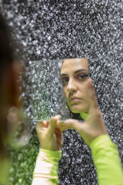 Mulher segurando espelho contra parede texturizada