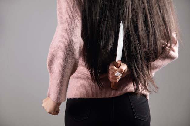 Mulher segurando faca nas costas