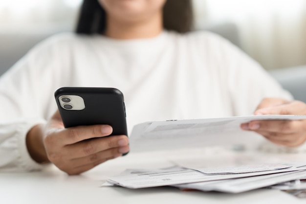 Mulher segurando fatura de papel e telefone celular