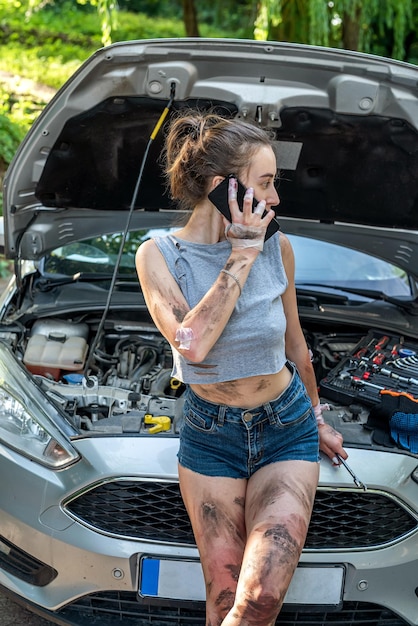 Foto mulher segurando ferramentas de trabalho em pé perto de carro quebrado e esperando ajuda motorista feminina está confusa e não sabe o que fazer