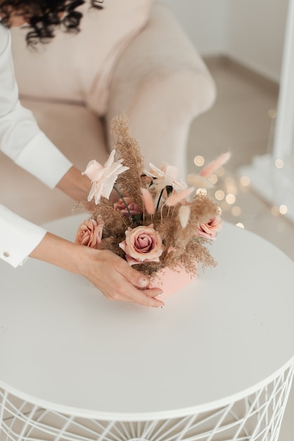 Mulher segurando flores artificiais minimalistas em uma caixa rosa