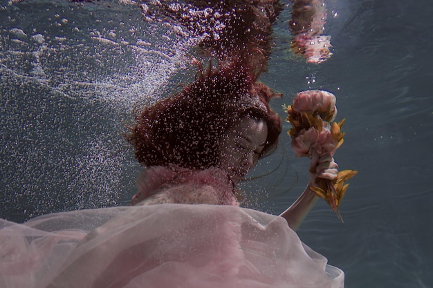 Foto mulher segurando flores enquanto nada na piscina