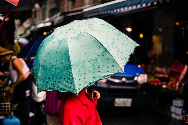 Mulher segurando guarda-chuva enquanto está de pé na cidade