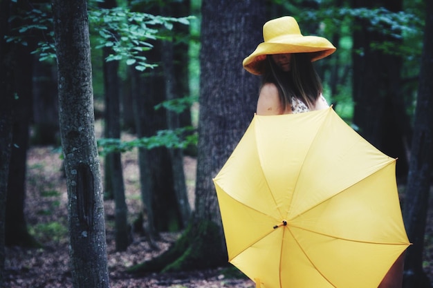Mulher segurando guarda-chuva enquanto está de pé na floresta