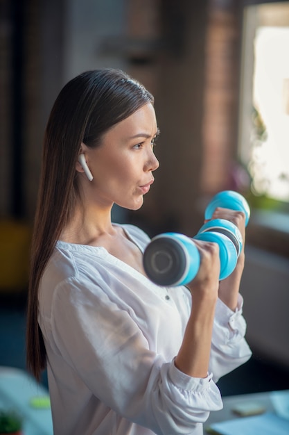 Mulher segurando halteres enquanto se exercita