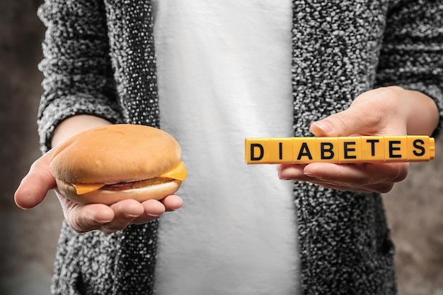 Foto mulher segurando hambúrguer e cubos com a palavra diabetes close-up